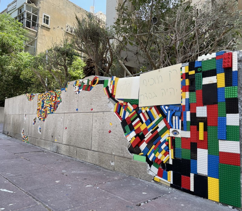 הבניין שנפגע מרסיסים, וחלקי הלגו שהודבקו. קרדיט צילום: רז שרור